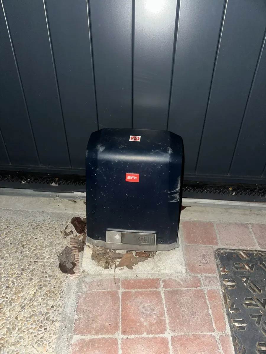 Motorisation BFT posée sur sa dalle, le long d'un portail coulissant gris anthracite