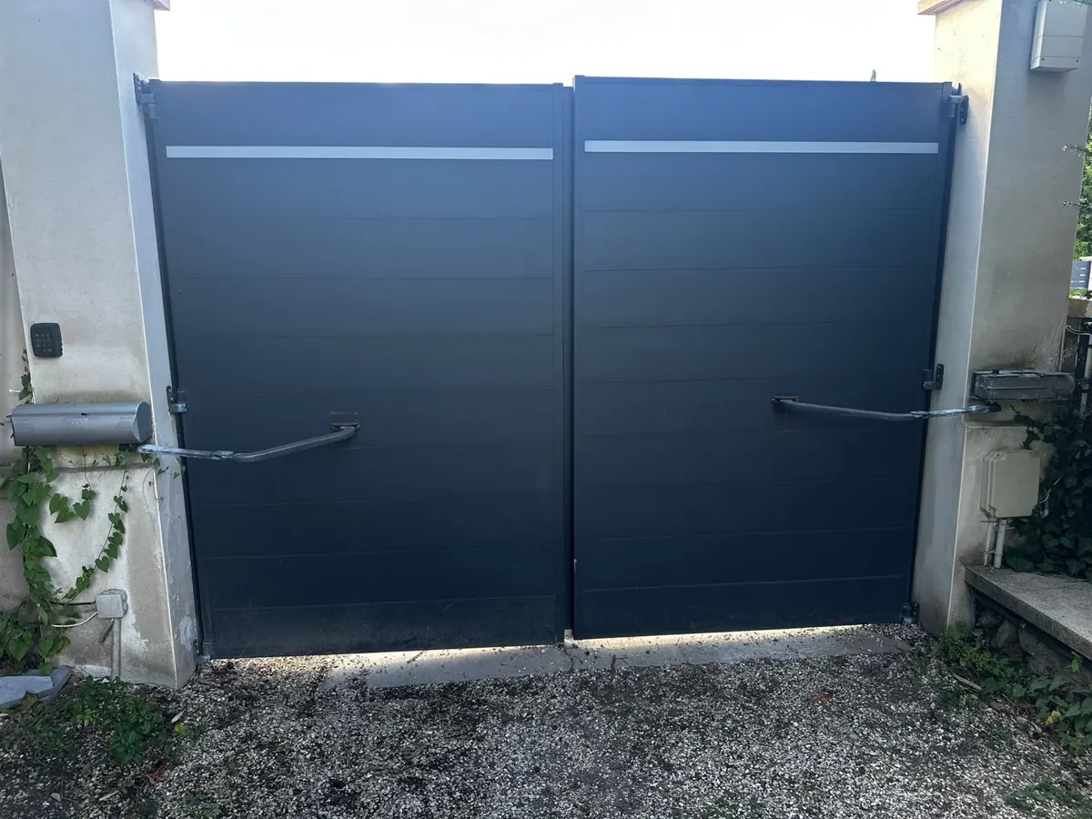 Portail battant en aluminium gris à deux vantaux, équipé de bras articulés