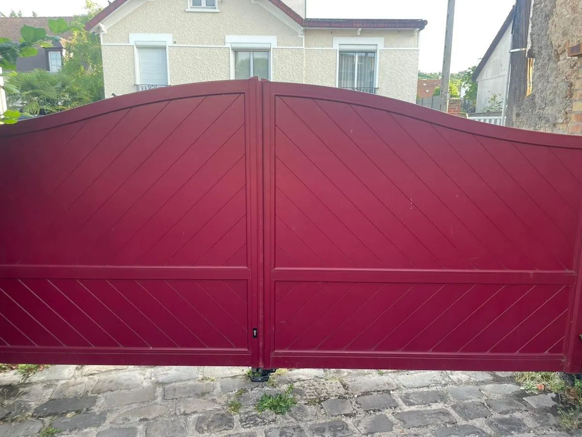 Portail battant en aluminium rouge à deux vantaux, remis en service après réparation de sa motorisation
