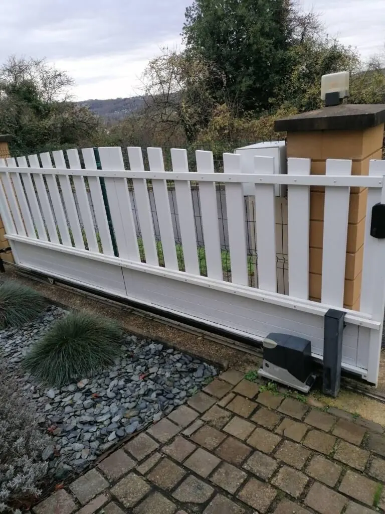 Portail coulissant en PVC blanc sur son rail, moteur en place au niveau du sol