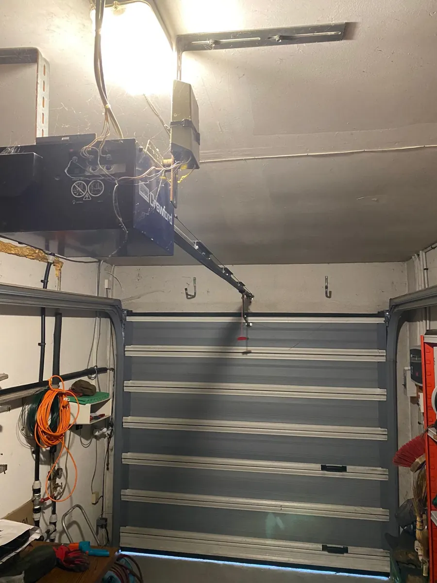 Porte de garage sectionnelle résidentielle et sa motorisation au plafond après intervention