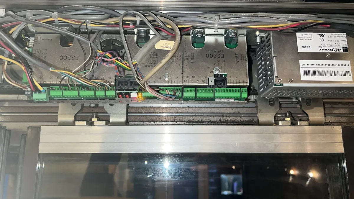 Rail, chariots et modules de commande d'une porte automatique coulissante en cours de révision